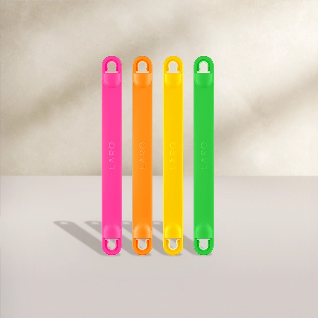BRITA LARQ Poignées en quatre couleurs : rose, orange, jaune et vert sur fond beige.
