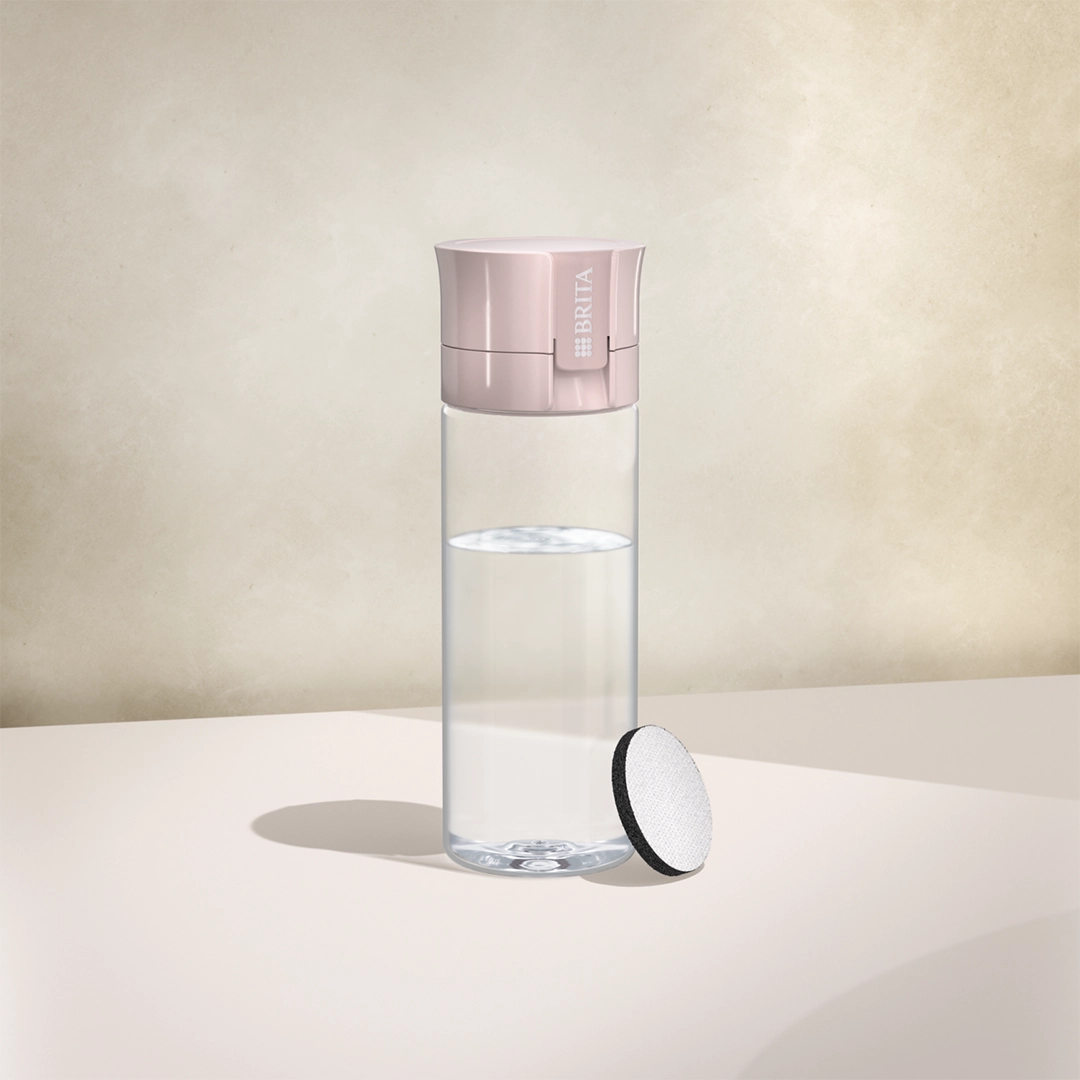 L'eau BRITA filtre une bouteille « Vital » de couleur mauve sur fond beige