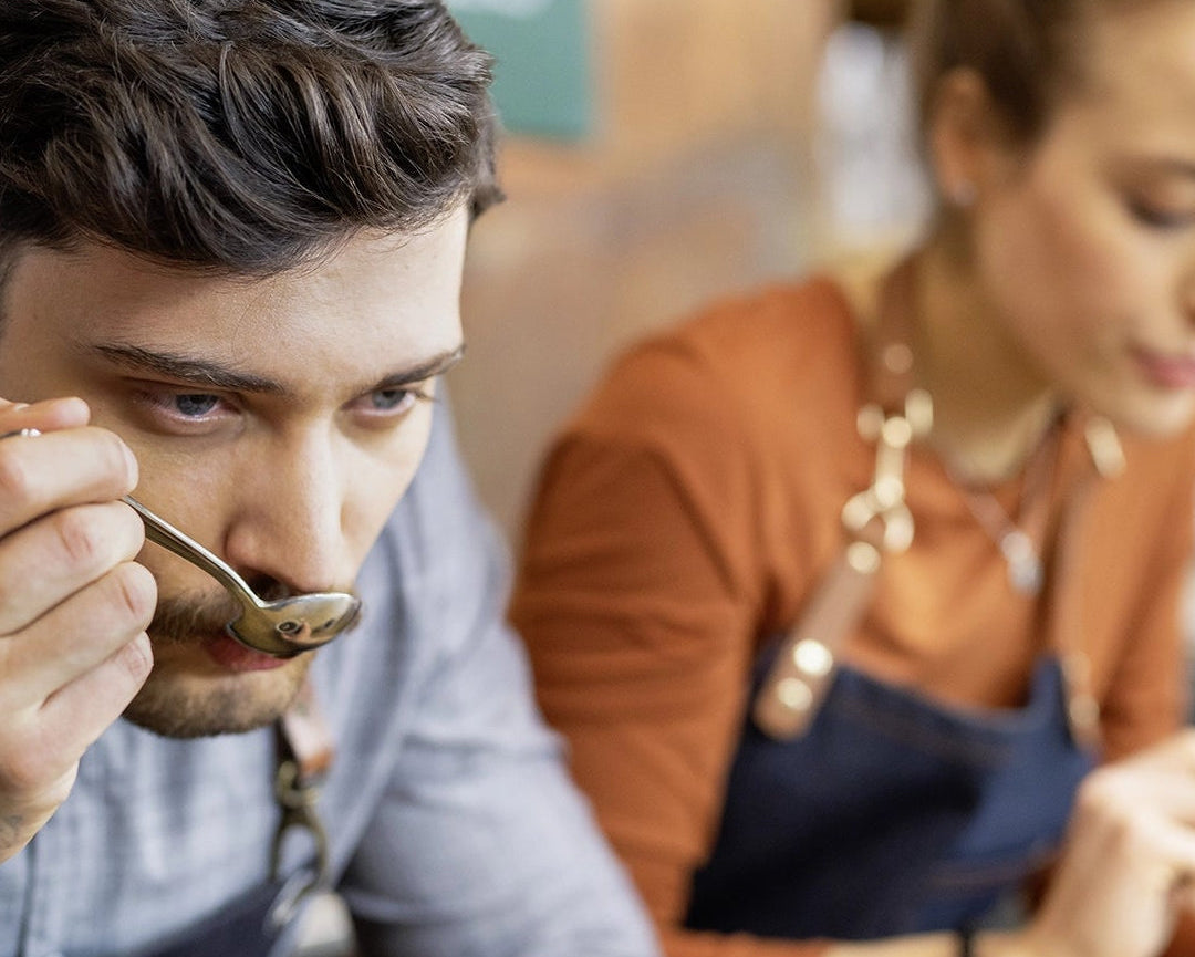 A young man and a young woman doing a sensory test with a cup of coffee.